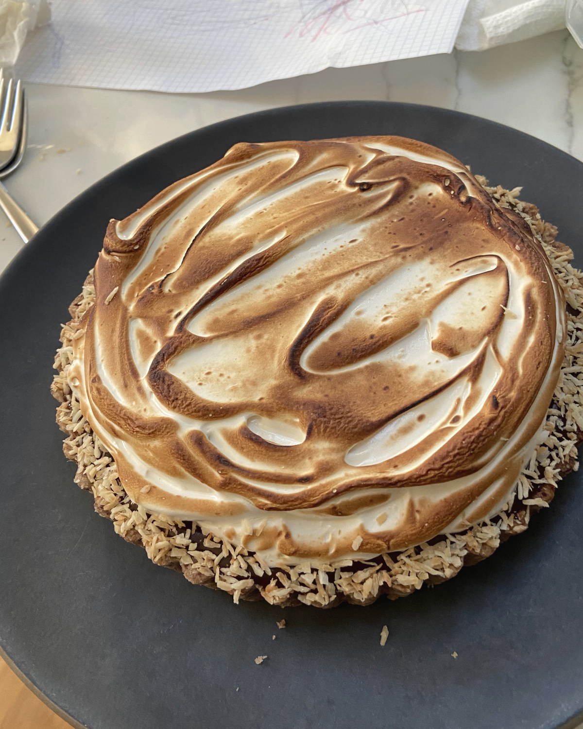 Chocolate passionfruit tart with toasted meringue on a dark plate