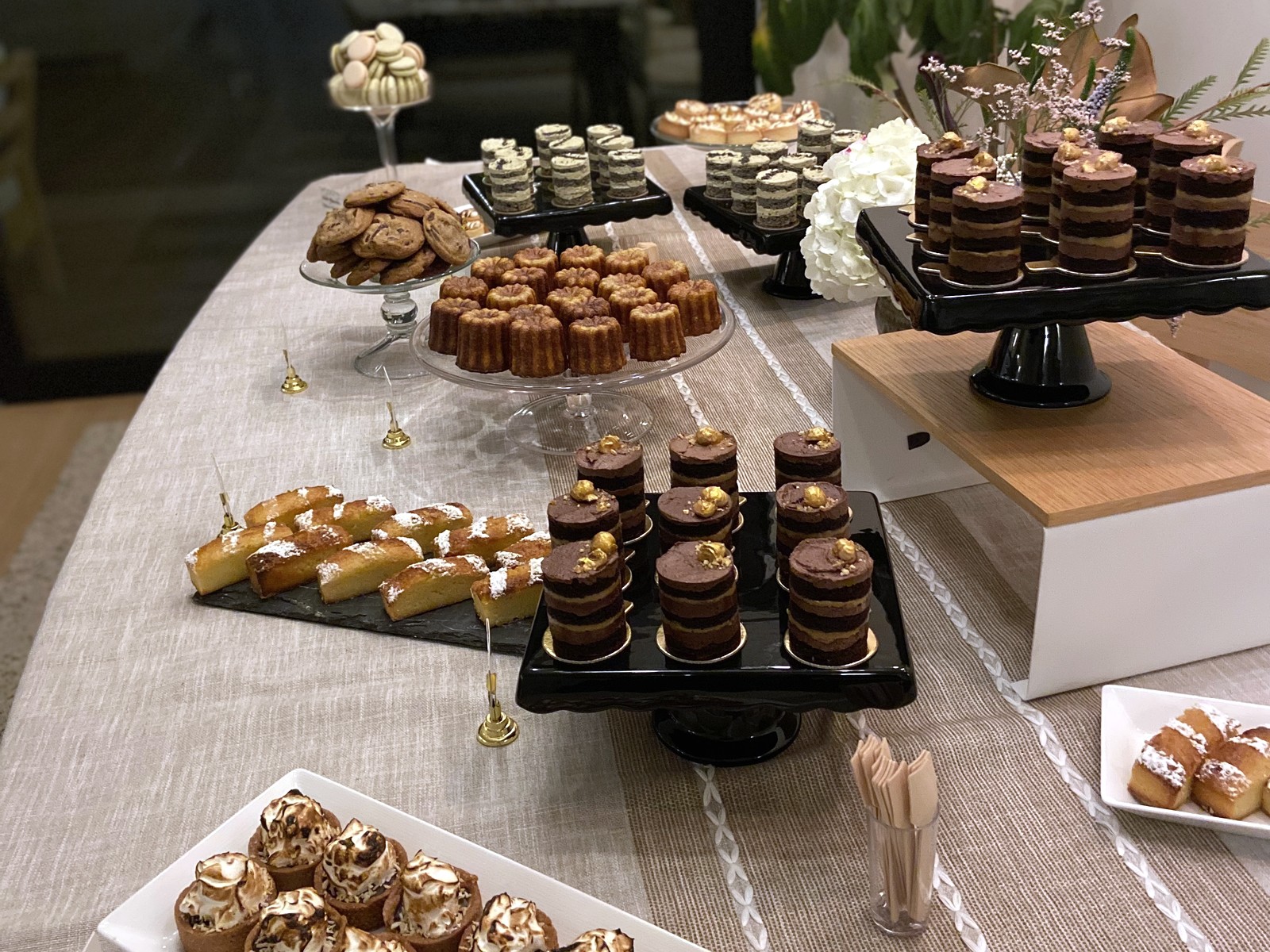 Event dessert table with layered cakes, cookies, caneles, and tartlets