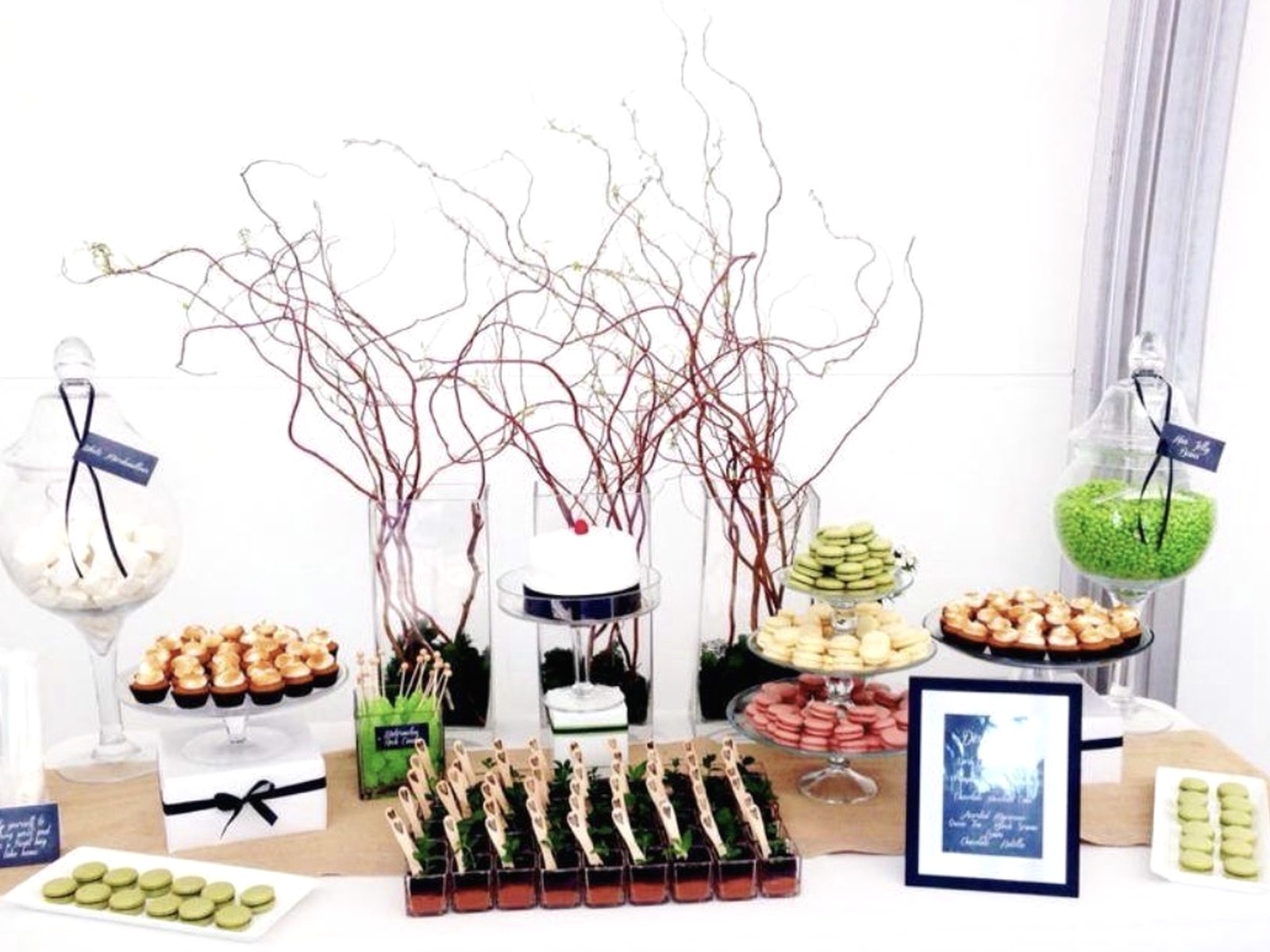 Dessert table with macarons, small bites, branches, and glass vessels